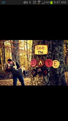 two people standing next to each other in front of a sign that says save the date