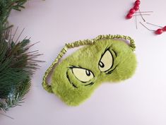 a green object with eyes on it next to pine branches