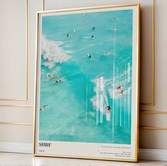 an aerial view of surfers in the ocean, framed in gold on a wall