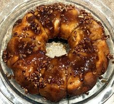 a bundt cake with pecans and caramel on top sits in a glass dish