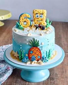 a blue cake decorated with the number six and an image of a pineapple on top