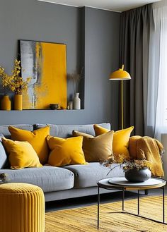 a living room filled with furniture and yellow pillows on top of a gray couch next to a window