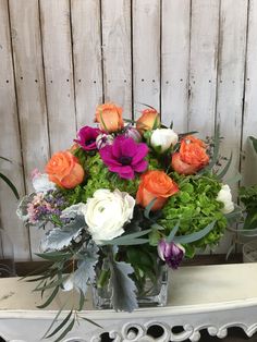 a vase filled with lots of different colored flowers