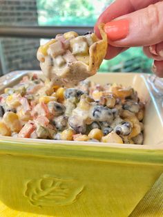 a person dipping some kind of food into a yellow bowl on top of a table