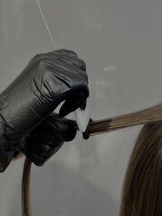 a woman getting her hair cut by a person with black gloves and rubber gloves on