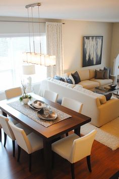 a living room filled with furniture and a dining table in front of a couch on top of a hard wood floor