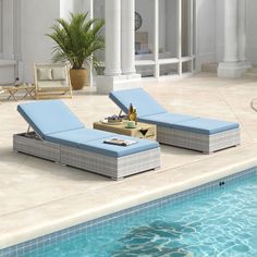 two blue chaise lounge chairs sitting next to a swimming pool in a home setting