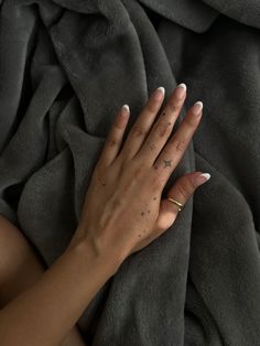 a woman's hand on top of a blanket with stars tattooed on her fingers