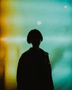 the silhouette of a person standing in front of a wall with multicolored lights