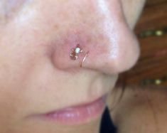 a woman's nose has a tiny pearled nose pin attached to her nose