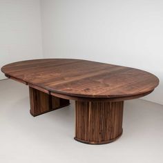 an oval wooden table sitting on top of a white floor