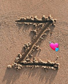 the letter z is drawn in the sand with a red heart on it's side