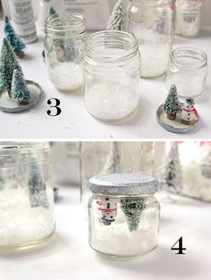 snow globes in glass jars filled with snow and christmas trees are shown on the table