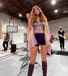 a woman in short shorts and boots standing on a stage with other people behind her