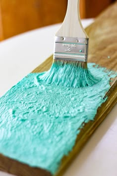 a paintbrush is being used to decorate a piece of wood with blue icing