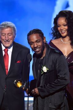 two men and a woman standing next to each other at an awards event with microphones