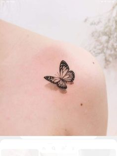 a small butterfly tattoo on the back of a woman's shoulder