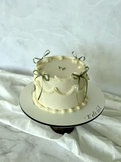 a white cake sitting on top of a table covered in frosted icing and bows