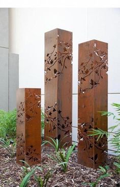 three tall metal sculptures sitting next to each other on top of a bed of dirt