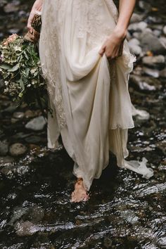 a woman in white dress walking through water