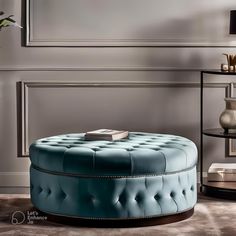 a round blue ottoman sitting on top of a floor next to a vase and lamp