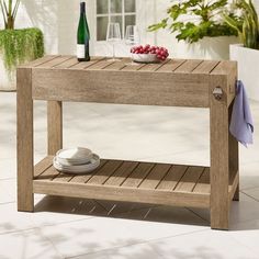 a wooden table with plates and wine glasses on it, next to a potted plant