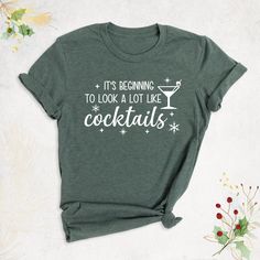 "Christmas Drinking Shirt, It's Beginning to Look a Lot Like Cocktails Shirt, Christmas Party Shirt, Holiday Xmas Shirt, Funny Christmas Shirt Hello, Thanks for your support. Your gladness comes first and all work is done with LOVE in here. Always keep your support, please:) Christmas Drinking Shirts are branded Bella+Canvas. Christmas Drinking Shirt Contents: - Solid colors: %100 Cotton. - Heather colors: %52 Cotton + %48 Polyester* This ultra-soft graphic tee is made from a comfortable cotton- Christmas Funny Shirt Ideas, Christmas Drinking Shirts, Christmas Party T-shirt With Graphic Print, Holiday Funny Print Short Sleeve Top, Funny Print Short Sleeve Holiday Top, Holiday Party T-shirt With Crew Neck, Casual Party Tops For Holidays, Funny Print Top For Christmas Gift, Funny Print Tops For Christmas Gifts