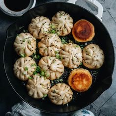 a skillet filled with dumplings and sauces next to a cup of coffee