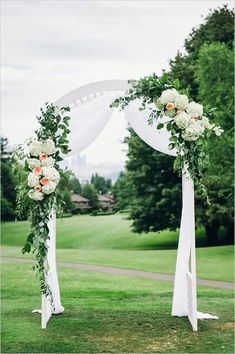 a wedding arch decorated with flowers and greenery for an outdoor ceremony at a golf course