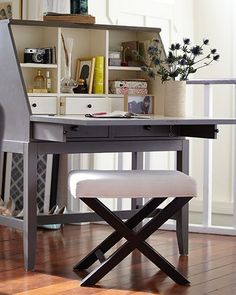 a desk with a chair next to it on a hard wood floor in front of a bookshelf