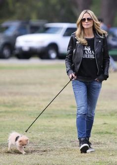 a woman walking her small dog on a leash