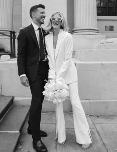 a man and woman standing next to each other in front of a building with columns