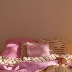 an unmade bed with pink and white pillows