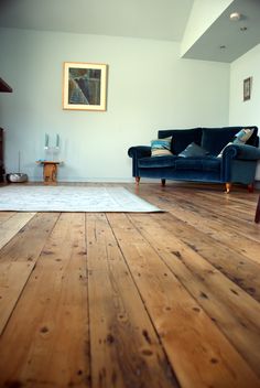 a living room with wood floors and a blue couch in the middle of the room