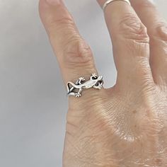 a person's hand with a silver ring on top of their finger and an animal in the middle