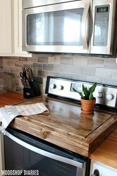 a potted plant sitting on top of a wooden cutting board next to an oven