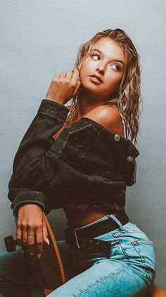 a beautiful young woman sitting on top of a skateboard