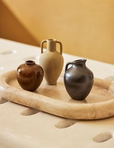 three vases sitting on top of a wooden tray