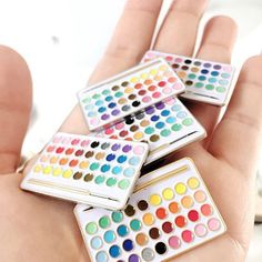 four different color palettes sitting on top of each other in someone's hand