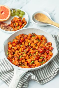 a pan filled with food sitting on top of a table next to a bowl of fruit