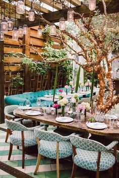 an outdoor dining area with blue chairs and tables set up for a meal, surrounded by greenery