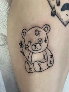 a small teddy bear tattoo on the leg