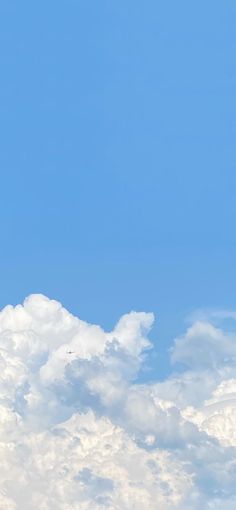 an airplane flying high in the sky with white clouds behind it and a blue sky