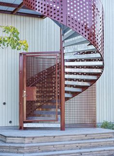 a metal spiral staircase next to a building with a wooden door on the bottom floor