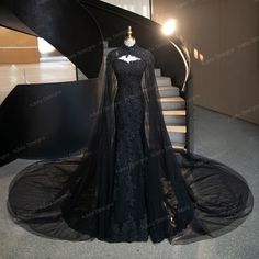 a black evening gown on display in front of a stair case at the entrance to a building