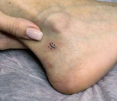 a woman's foot with a small smiley face tattoo on the left side of her toe