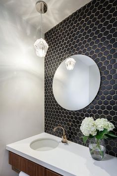 a white sink sitting under a round mirror