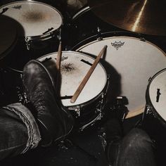 a person with their feet propped up on drums and the drumsticks in front of them