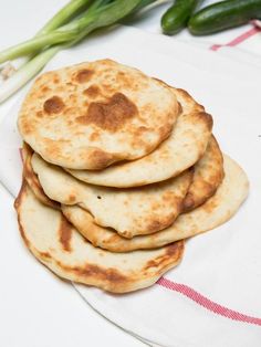 a stack of pancakes sitting on top of a white plate next to some green onions