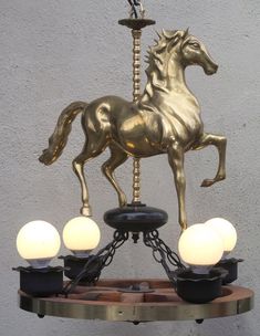 a golden horse statue sitting on top of a table next to three lights and a lamp